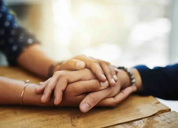 Soutien et réconfort lors d'un deuil avec deux personnes se tenant la main.