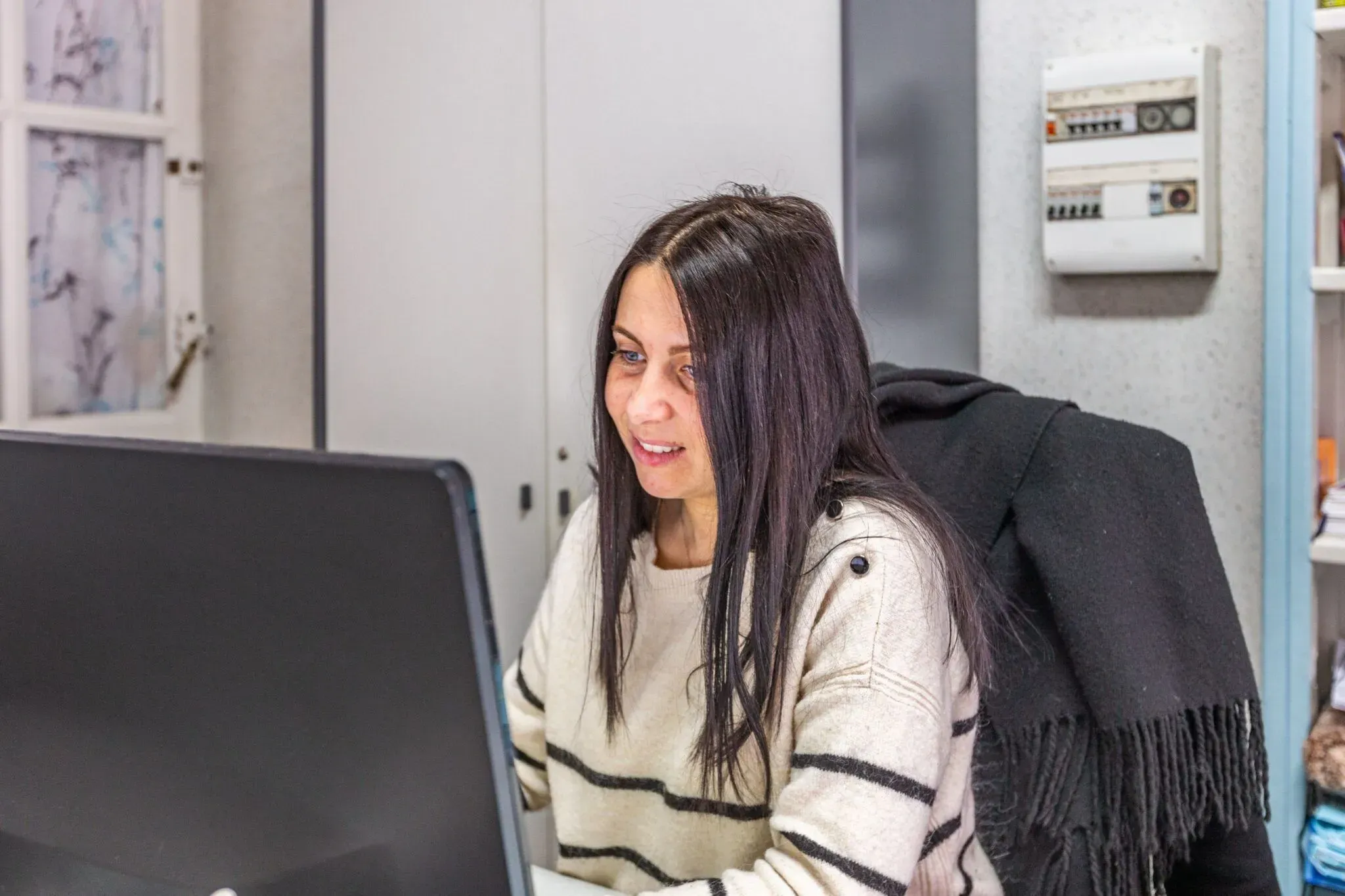 onseillère funéraire souriante travaillant sur un ordinateur à son bureau.