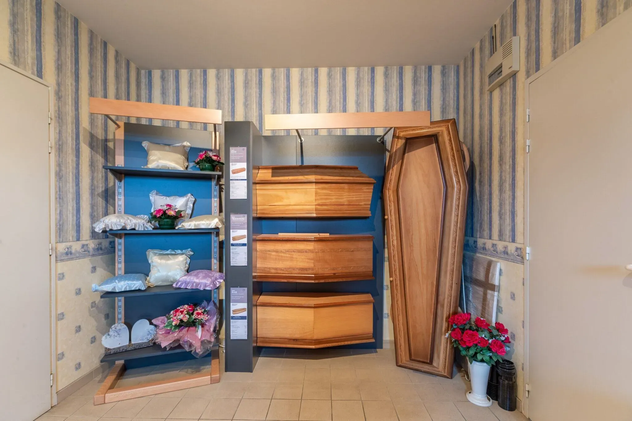 Modèles de cercueils en bois et capitons présentés dans un salon funéraire.