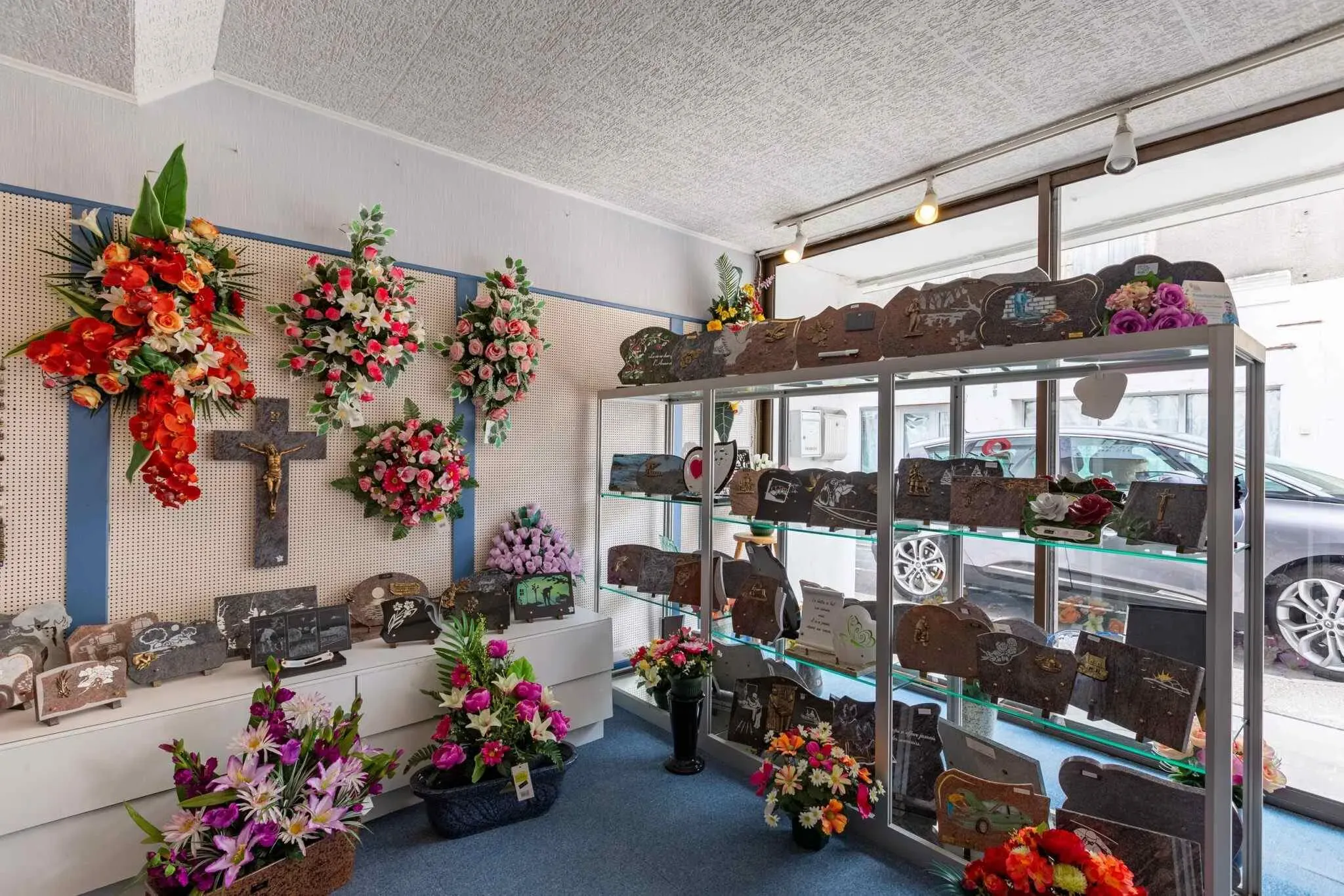 Articles funéraires, croix et fleurs de deuil exposés en boutique.