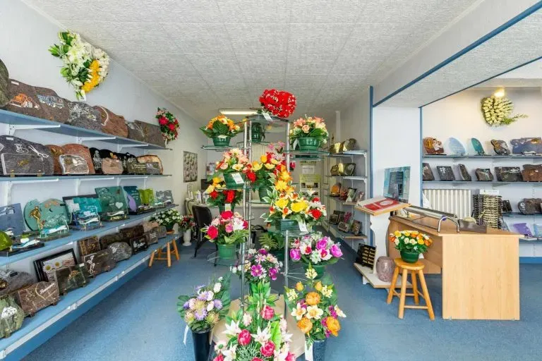 Magasin d'articles funéraires présentant fleurs artificielles et plaques de deuil.
