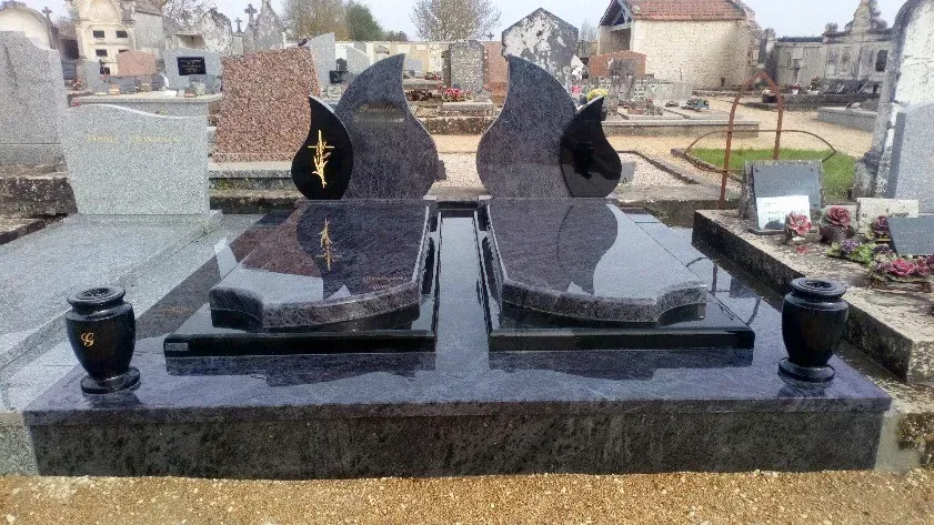 Monument funéraire familial en granit poli avec deux stèles en forme de flamme.