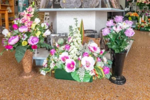 Compositions florales de deuil et fleurs artificielles présentées en magasin funéraire.